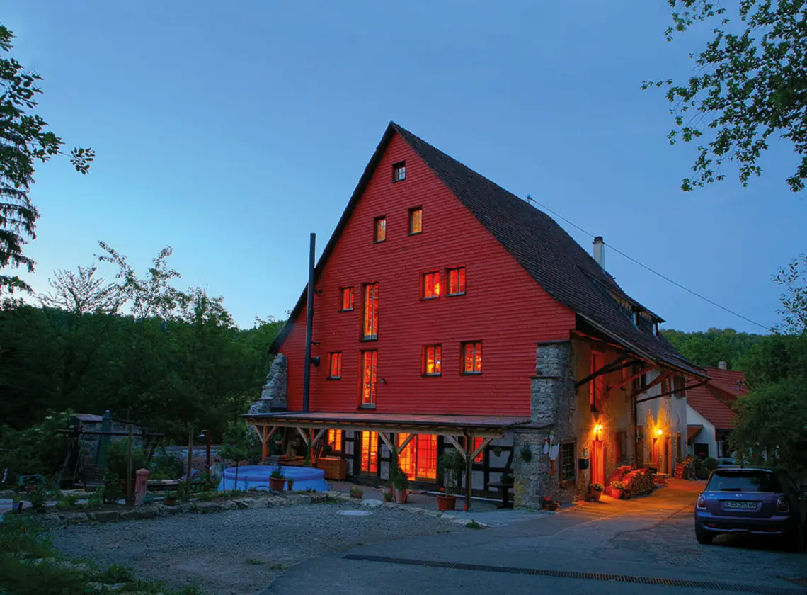 Das Geburtshaus Horb in der Dämmerung, die Fenster des roten Holzhauses sind erleuchtet