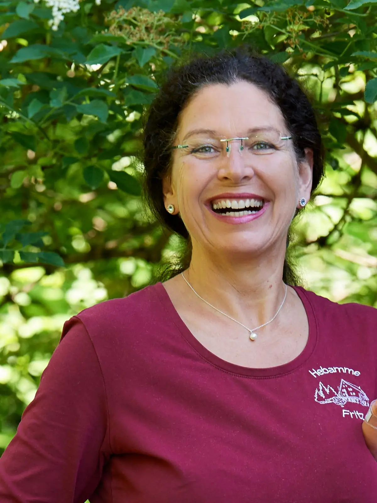 Dorothea Fritz, Hebamme und Inhaberin des Geburtshauses, lacht im Garten des Hauses in die Kamera
