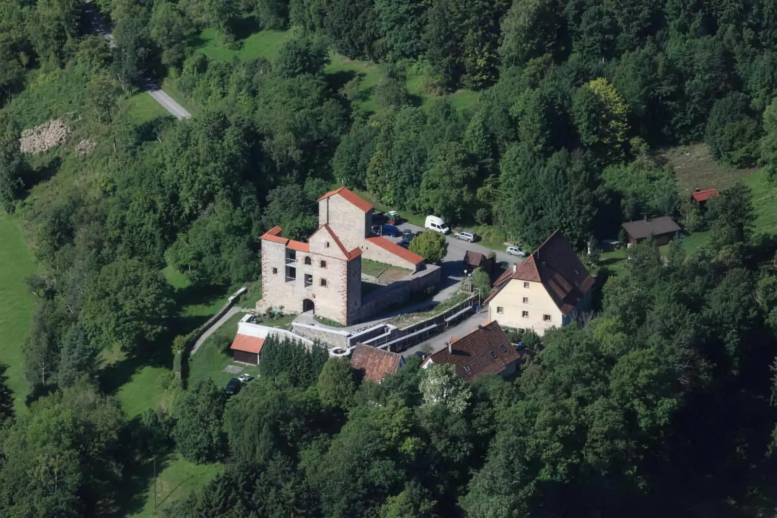 Luftbild der Burg Dießen: das Geburtshaus und der alte Bergfried, ringsum dichter Wald
