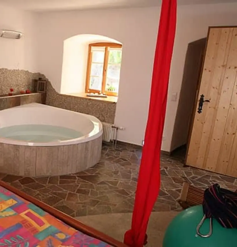 Geburtsraum mit runder Wanne, rotem Halteseil und Fenster in der alten Mauer